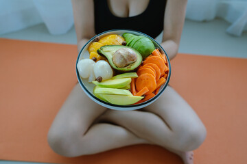 A woman enjoys a fresh, healthy salad made with organic vegetables at home, promoting a balanced...