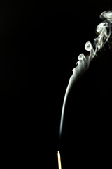 Burning incense with smoke on a black background.