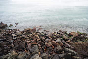 Large, dark rocks on the shore of the Atlantic Ocean. Breakwater wall. Nautical structure