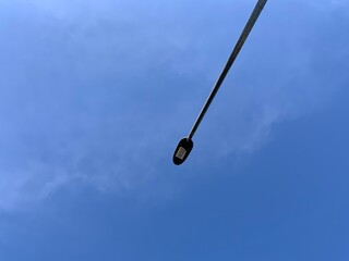 Street lights with a blue sky background with soft clouds, taken from a low angle