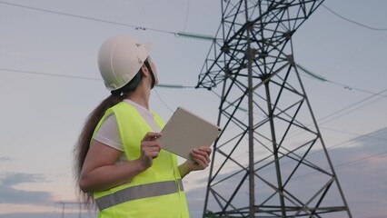 an electrician works with a tablet at a large power plant supplying electricity, an energy engineer...
