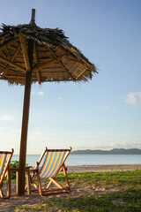 A beautiful tropical deck chairs and straw umbrellas by ocean in El Nido, Palawan, Philippines. A romantic atmosphere by the shore, calm sea and nice weather, perfect themes summer vacation in Asia