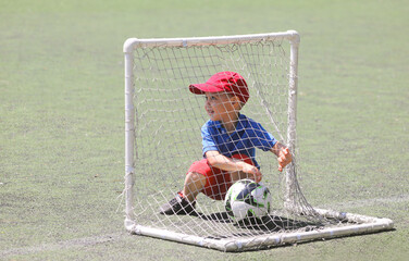 Little  boy plays football at a sports school.