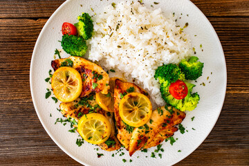 Lemon chicken escalopes with rice on wooden table