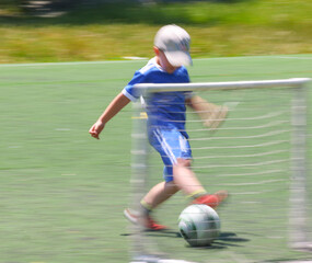 little  boys plays football at a sports school .Blur.