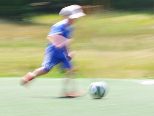 little four -year-old boys plays football at a sports school .Blur.