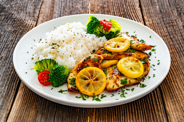 Lemon chicken escalopes with rice on wooden table