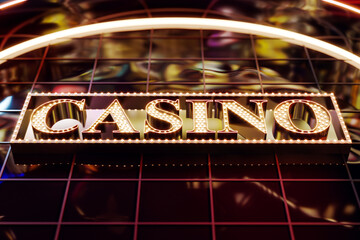 Glowing neon casino signboard with bright retro lights on modern glass building at night, viewed from bottom angle for vintage promotion concept. 3D Rendering