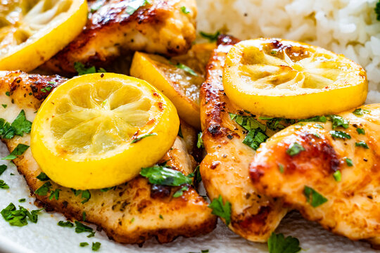 Lemon chicken escalopes with rice on wooden table