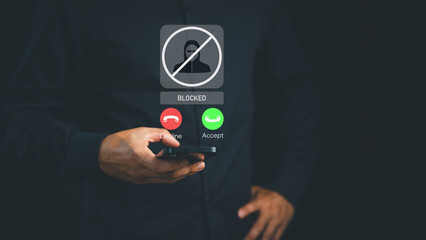 Smartphone screen shows a hacker icon and blocked symbol as a user blocks a scam call, highlighting...