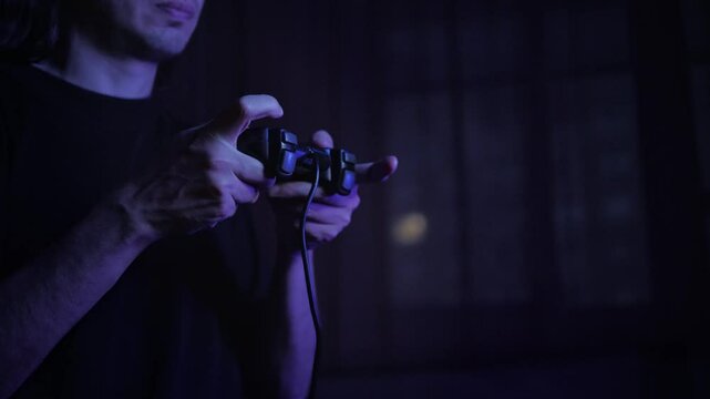 An immersed and focused mood is captured by a close-up of hands expertly manipulating a video game controller, dimly lit by a blue glow, suggesting intense gameplay in a dark room