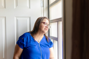 Hopeful senior woman gazing through window, contemplating life's journey