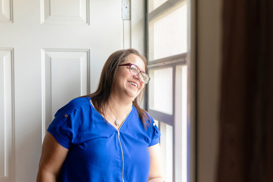 Happy senior woman smiling and looking out the window at home