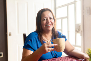 Happy senior woman smiling and holding mug while sitting at home
