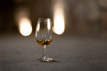 Glass of aged wine in a stone wine cellar, capturing the quiet, authentic atmosphere of traditional wine tasting and maturation.