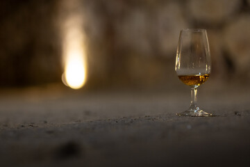Glass of aged wine in a stone wine cellar, capturing the quiet, authentic atmosphere of traditional wine tasting and maturation.
