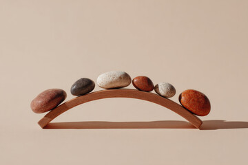 Smooth balance stones forming arch on wooden bridge, neutral beige background, symbolizing harmony, stability, and calmness in minimalist style