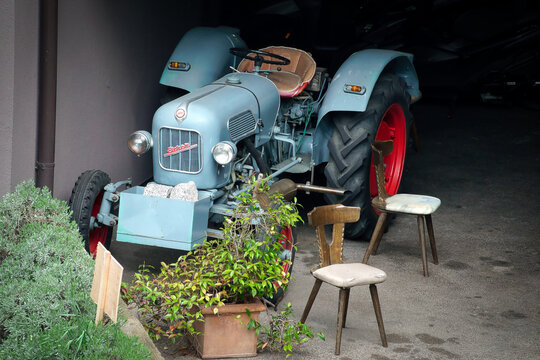 Ein alter Eicher Diesel Traktor steht in einer Garage neben St&uuml;hlen