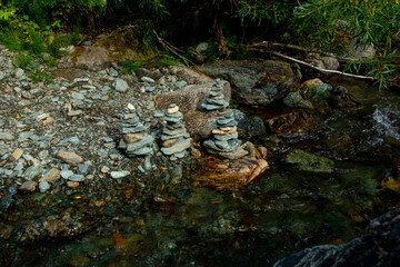 Pyramids of stones among the waters of a mountain stream.  Stacks of stones left by tourists