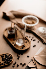 Empty glass filled with ice cubes standing on a cozy kitchen surface. Beginning of iced latte preparation, rustic lifestyle mood.