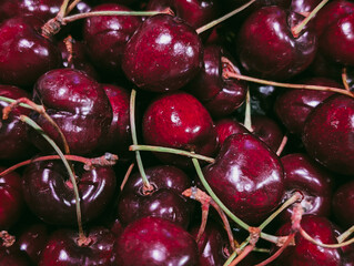 Horizontal background of juicy red cherries with green stems
