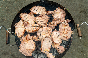 Grilled meat steak on stainless grill depot with flames on dark background. Food and cuisine concept.