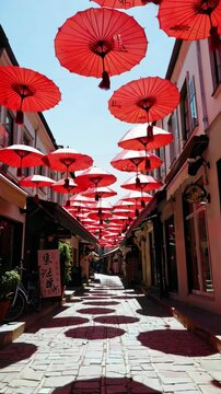 Red umbrellas hanging over narrow cobblestone street