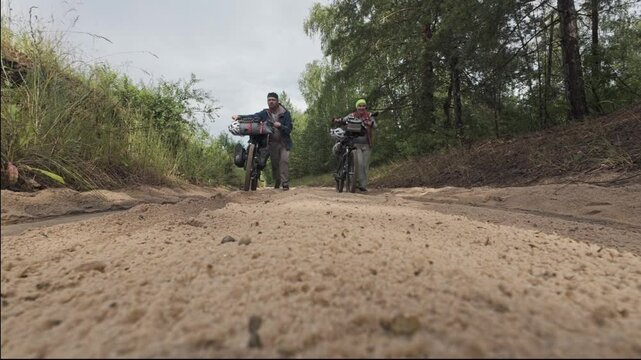cycling in nature in wild places, bike-packing. Husband and wife pushing bicycles in the sand