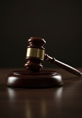 A wooden judge's gavel on a wooden table against a dark background. Concepts of justice, law, and auctions. Professional law practice backdrop with copy space for text and a court trial background	
