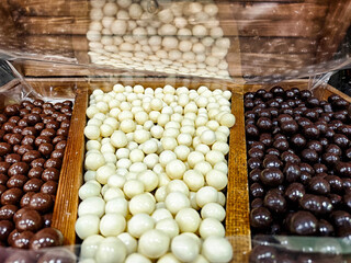 Colorful display of assorted candies arranged in wooden trays at a market stall in daylight