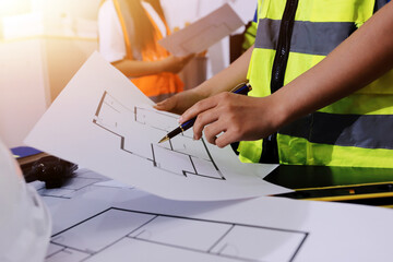 Closeup of team of industrial engineers meeting analyze machinery blueprints consult project on...