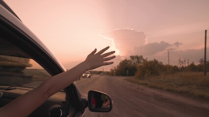 girl from a car catches wind with her hand at sunset, drive a car on a journey, drive on an asphalt...