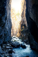 Scenic river flow through Rosenlaui glacier gorge with sunlight in Switzerland
