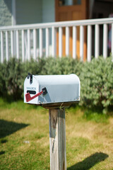 White american mailbox set on wooden post at front of house