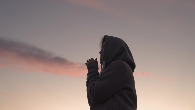 Girl praying on a pink sky background, believe in good good, ask for help, dream looking up, motivation inspiration outdoors, woman thinks meditating, wanderlust concept, heavenly light.