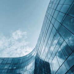 Low-angle view of a modern, curved glass skyscraper reflecting a partly cloudy sky