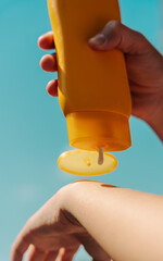 Teen applying sunscreen on face, arm, and leg under direct sun. Summer skincare, blue sky, beach background, and beige hammock. Sun protection routine, outdoor wellness