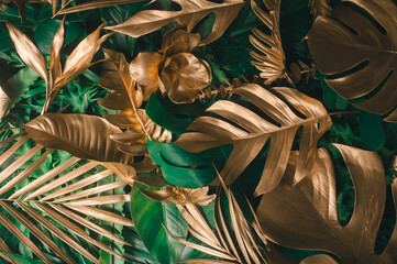 Creative nature background. Gold and green tropical Monstera and palm leaves. Minimal summer...
