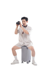 Fototapeta premium Man With Camera: A cheerful man wearing casual attire sits atop his luggage with a camera in hand, ready to capture memorable moments on his trip. Reflecting the spirit of exploration and discovery