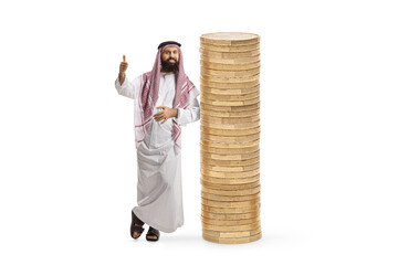 Saudi arab man in a traditional thobe leaning on a pile of coins and gesturing thumbs up