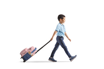 Full length profile shot of a boy walking and pulling a schoolbag