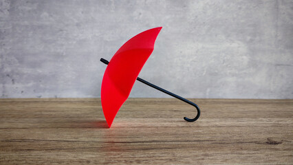 Red Umbrella on Wooden Table, Symbolizing Protection, Insurance, and Risk Management Concepts