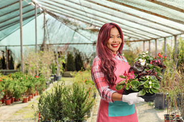 Asian female gardener holding flower pots