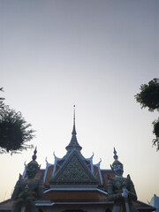 Fototapeta premium Majestic Thai Temple Architecture A Low-Angle View of Intricate Roofline and Guardian Statues