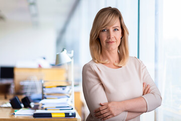 Smiling blond haired business woman standing at the office