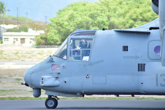 Gray military helicopter on a tarmac, side view, with cockpit visible.