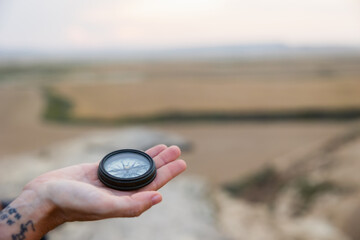 Hand holding compass with blurred countryside in background. Lifestyle. Hiking. Bardenas Reales.