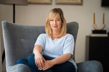 Portrait of a blond haired woman relaxing in an armchair at home