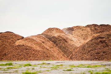 mountains of wood chips against a grey sky