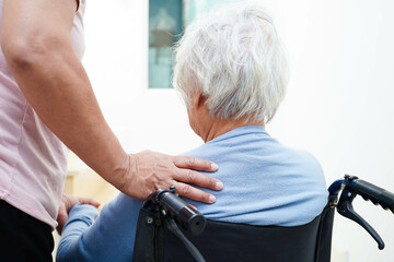 Caregiver help Asian elderly woman disability patient sitting on wheelchair in hospital.